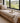 Wooden bench with cushions and a view of a rural landscape through large windows.